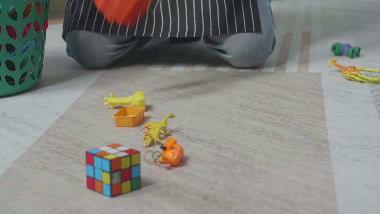 cerca de las manos del ama de llaves masculino recoger los juguetes a la canasta de plástico en la habitación desordenada