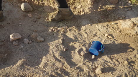 el excursionista deja caer la taza de campamento en la caminata por el desierto en la suciedad y las rocas
