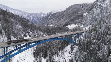 winter ballet: cars glide across paulson bridge, snow-blanketed peaks rise