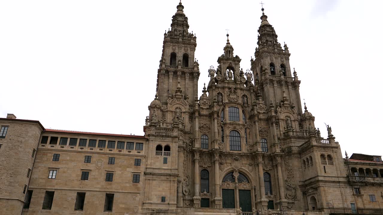 Panning shot of famous Santiago de Compostela Cathedral against cloudy sky - Ancient historical pilgrim church in Spain - bottom up