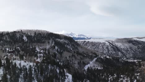 amazing winter landscape with road in the forest and high mountain peak on horizon