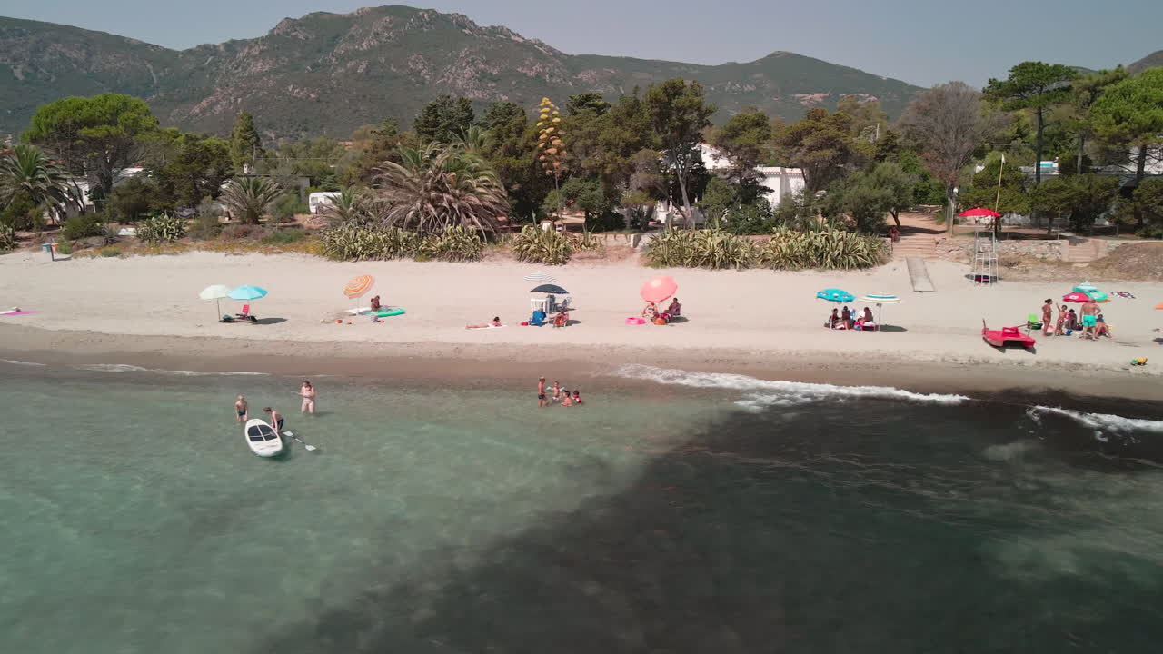 turista de familias bajo sus grandes sombrillas disfrutando de las vacaciones de verano en la costa arenosa de cerdeña, isla de italia