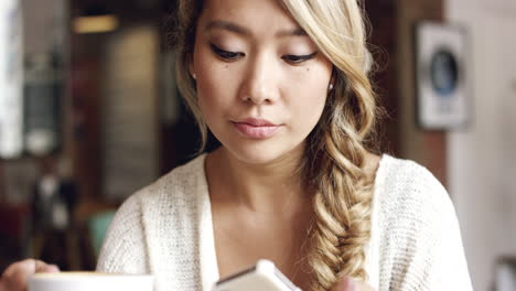 asian woman using smartphone touchscreen  in cafe drinking coffee