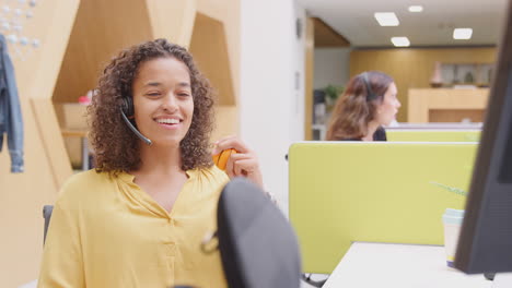 mujer de negocios con auriculares jugando con una pelota de estrés hablando con la persona que llama en el centro de servicios al cliente