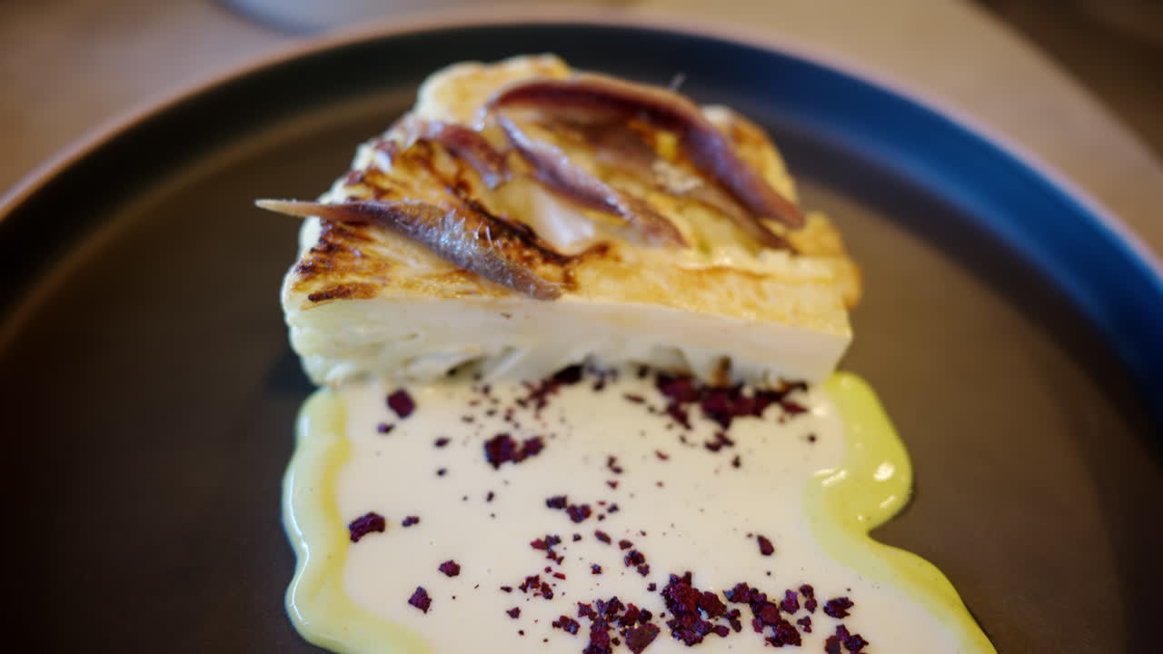 Cauliflower steak with a white sauce on a black plate