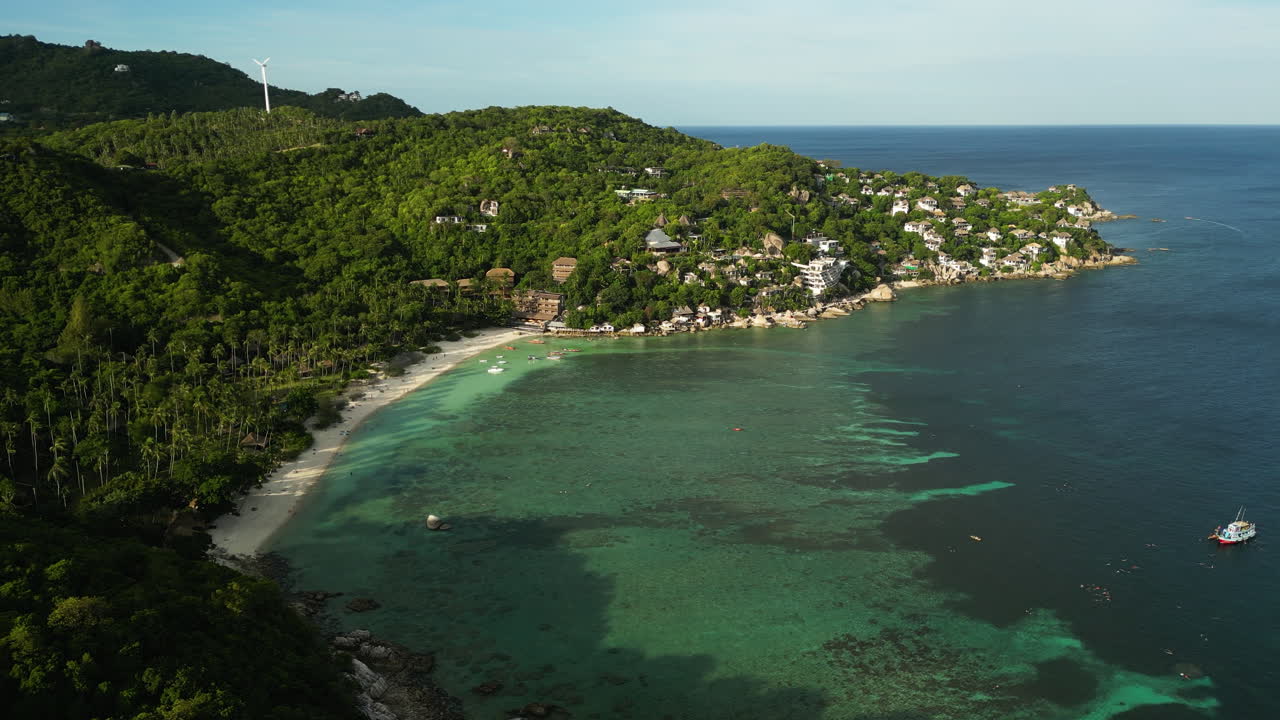vista aérea de la playa de arena con aguas claras de la bahía frente a las colinas verdes en koh tao al atardecer dorado