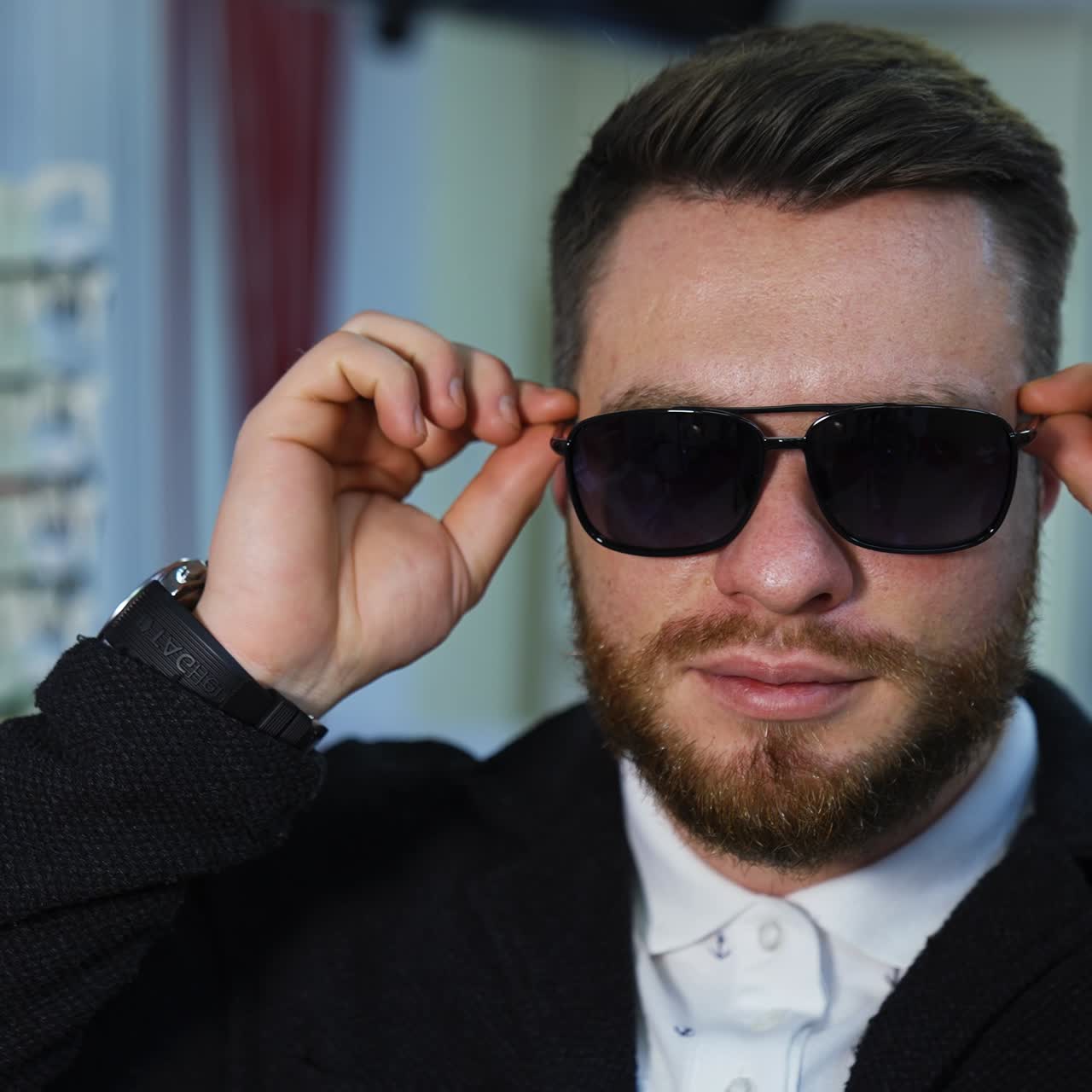 Facial portrait of a man in new black glasses in the shop. Happy businessman in sunglasses looking at camera. Man choosing new glasses in the optical store
