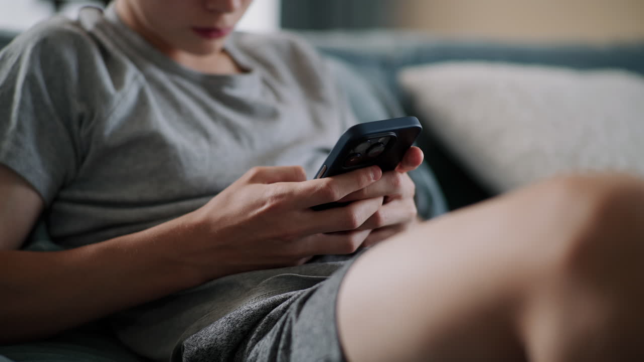 подросток использует смартфон на диване
