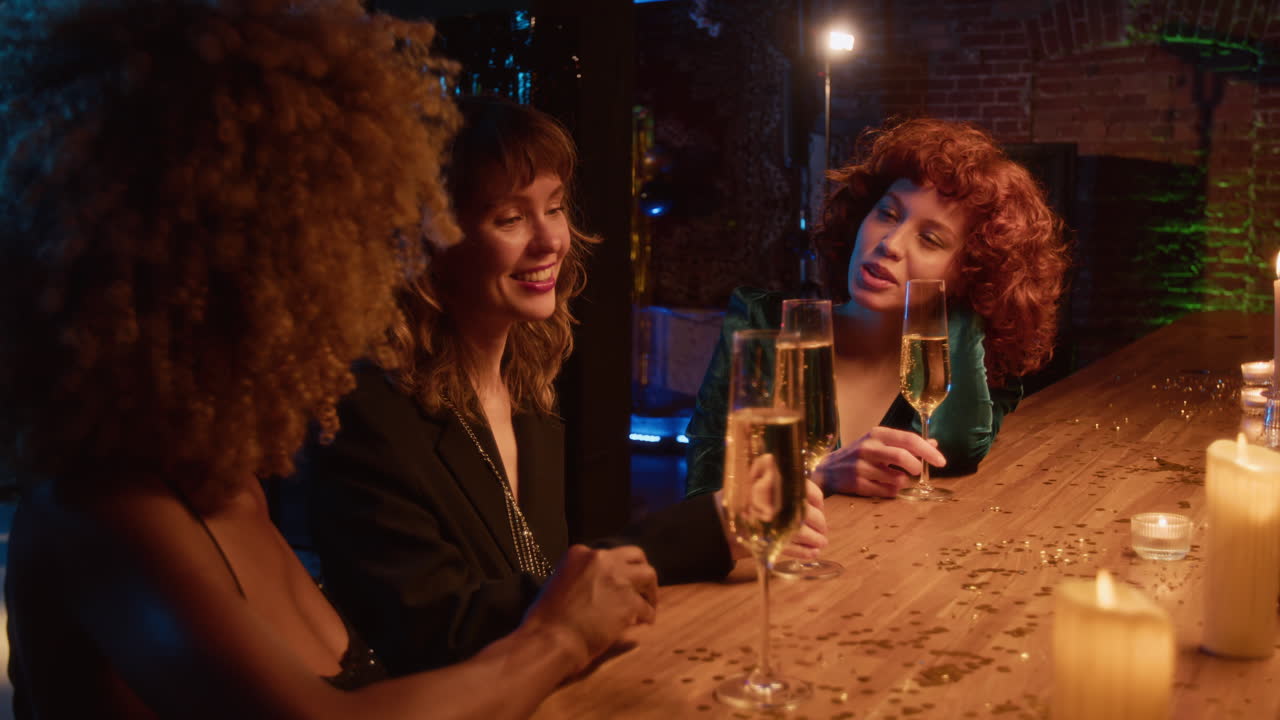 Three women celebrating with champagne at a bar
