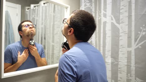 Leftward-pan-showing-a-man-wearing-glasses-as-he-shaves-his-beard