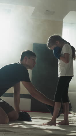 el instructor muestra la posición estable de los pies del niño en el gimnasio de boxeo. el entrenador de lucha enseña a la niña kickboxing en el club deportivo en cámara lenta. artes marciales