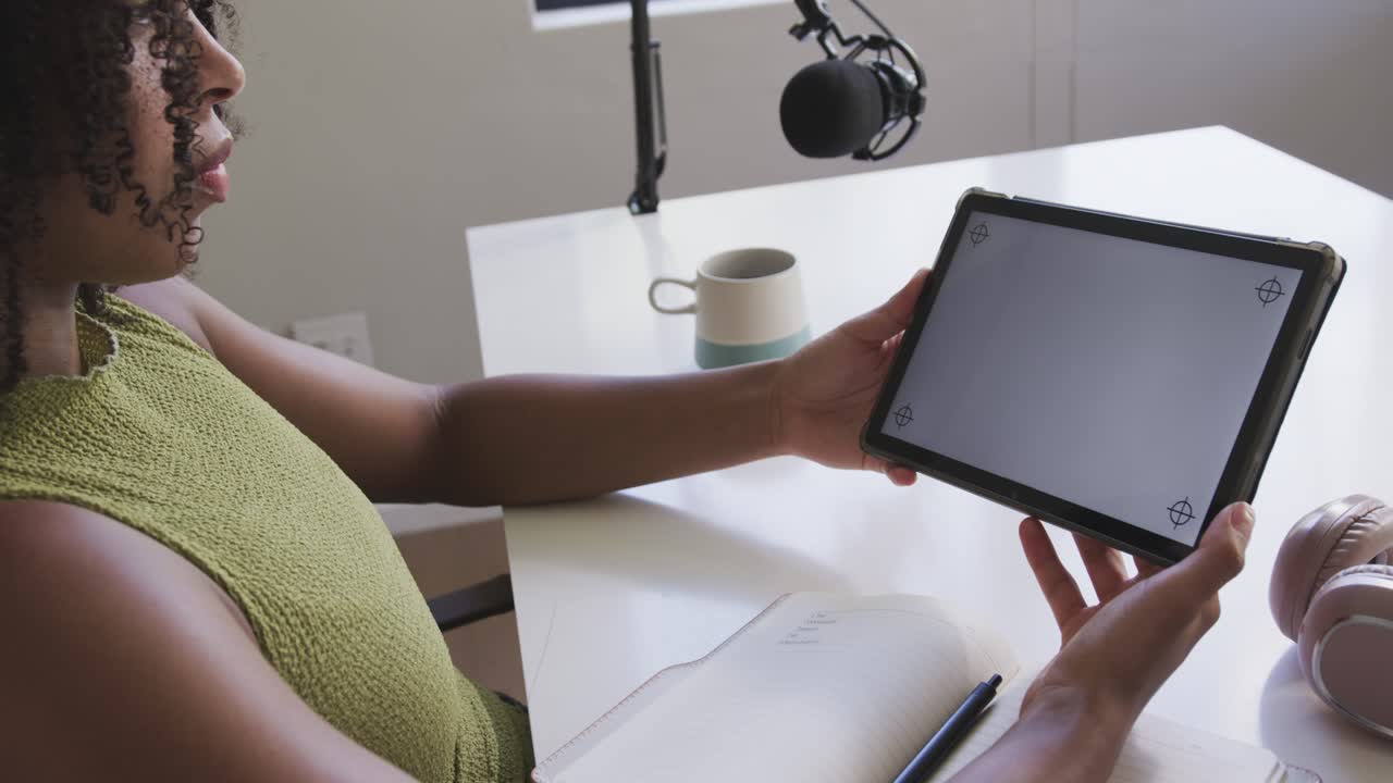 African American woman seeing tablet markers, angling tablet for shot with mic at desk, copy space