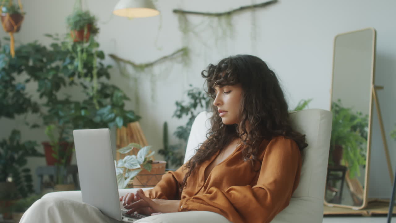 Woman Using Laptop in Room with Houseplants
