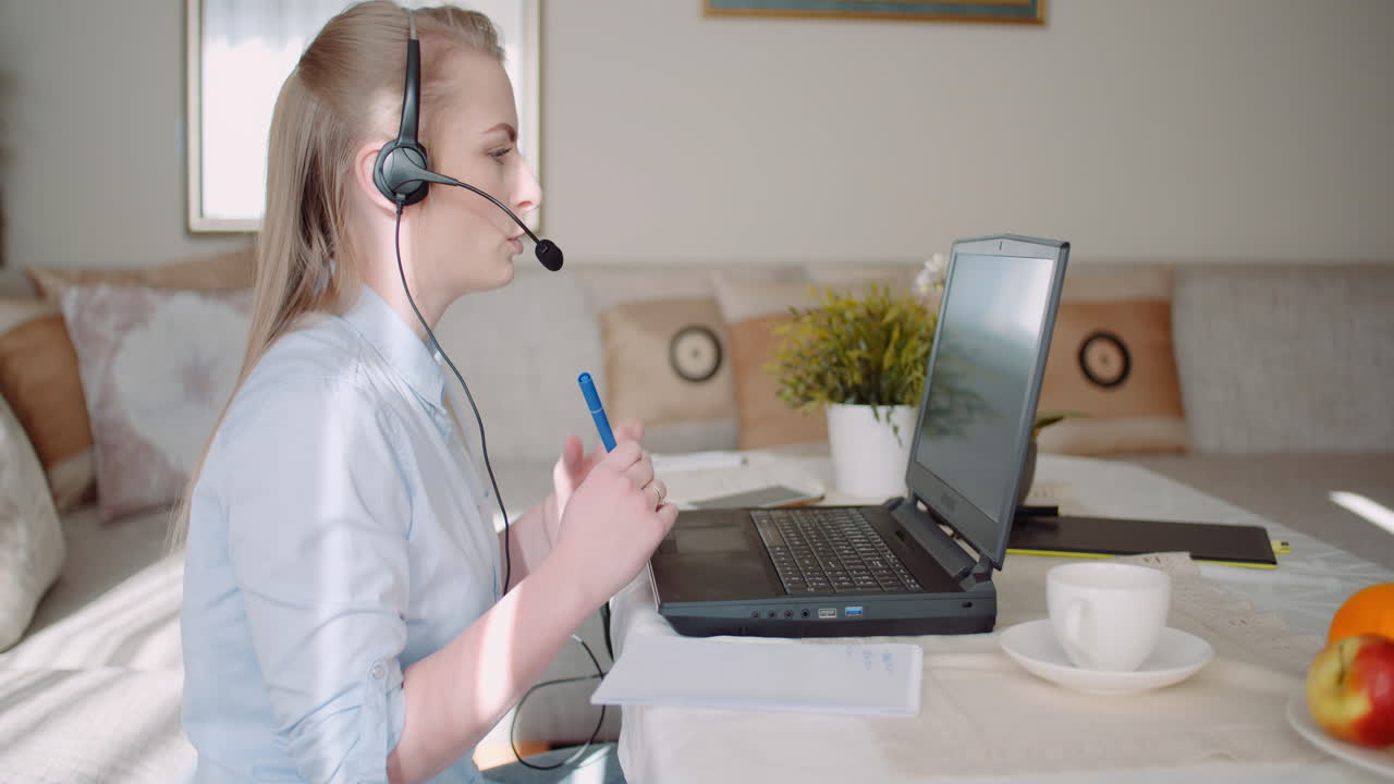 Representante de Ventas con Auriculares Hablando con Cliente y Realizando Videoconferencia en Portátil 2