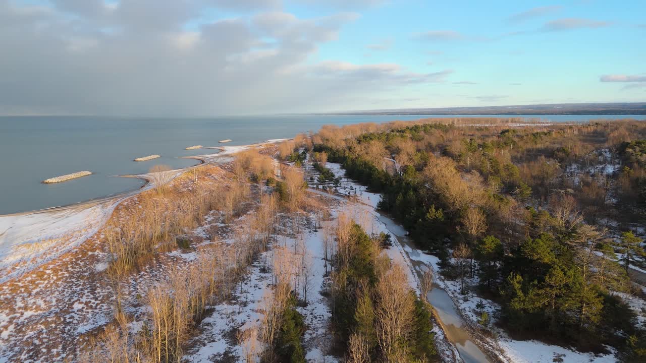 Aerial push in on Presque Isle State Park in the winter at golden hour.