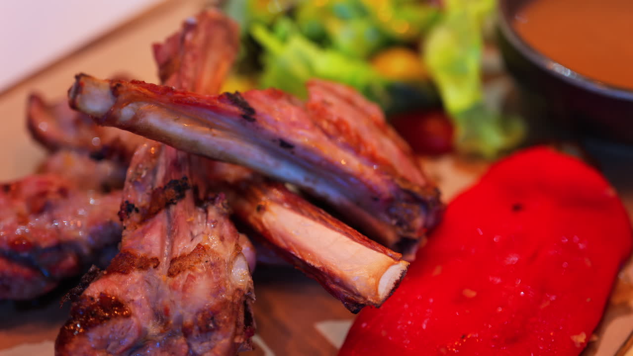 Close up of lamb chops with sauce and a side salad on a plate at a restaurant