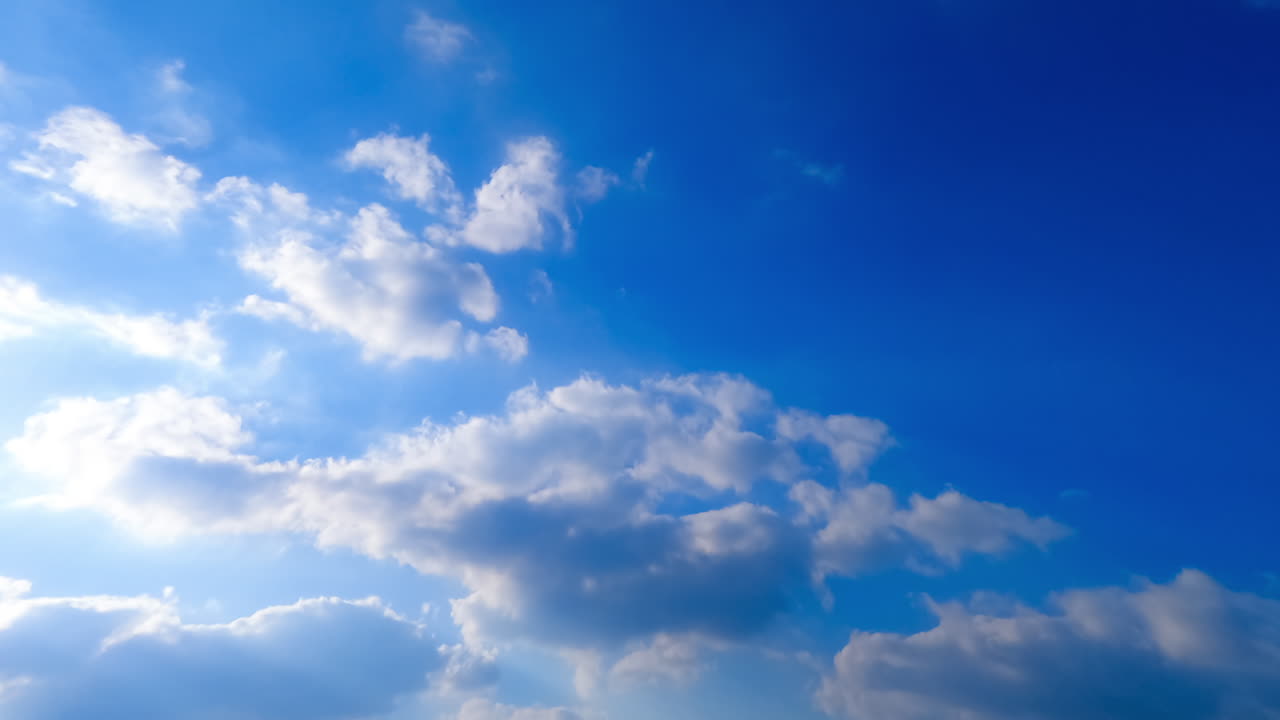 Soft fluffy clouds are lit with bright summer sun. Beautiful cloudscape transforms in the sky. Low angle view. Timelapse.