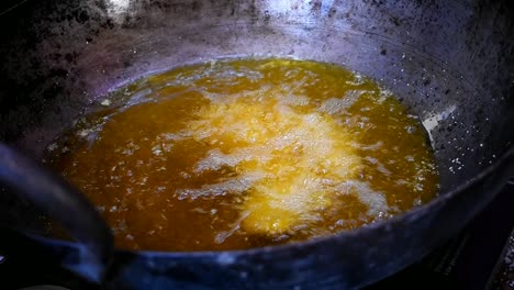 close up of a mans hand putting dough into oil for deep frying