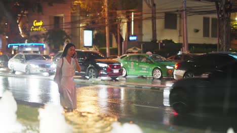 woman walking across a rainy city street at night