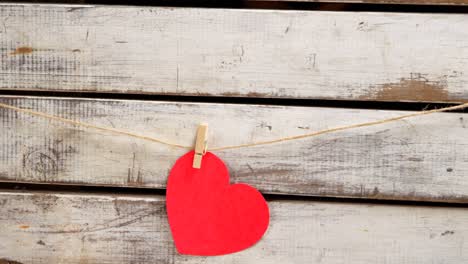 person pinned a red colour paper heart against wooden surface 4k