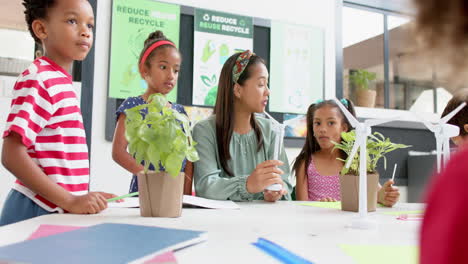 in school, teacher discussing wind energy with students using wind turbine models