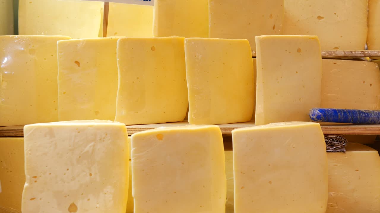 una pila de bloques de queso amarillo para la venta en un mercado