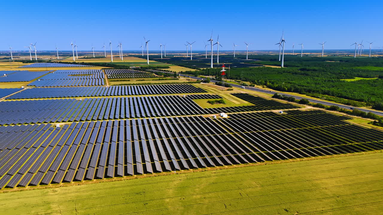 Solar and wind energy grid. Solar panels and wind turbines spread across the countryside, showcasing renewable energy on a sunny day
