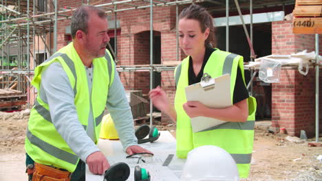 constructor en el sitio discutiendo el trabajo con la aprendiz femenina