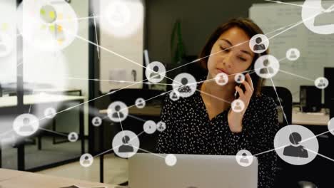 Animation-of-network-of-connections-with-icons-over-biracial-businesswoman-at-office