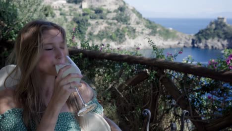 attractive young girl in a balcony enjoying a glass of lemonade in an island resort in italy