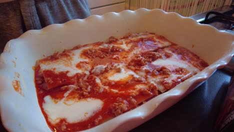queso espolvoreado encima de bechamel y salsa boloñesa en un plato de lasaña a mano