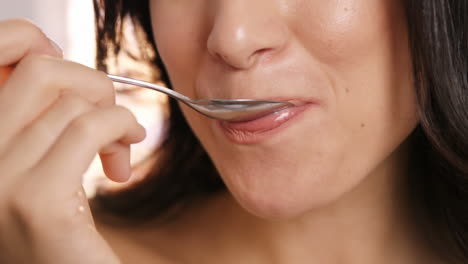 cerca de una mujer marrón comiendo un yogur