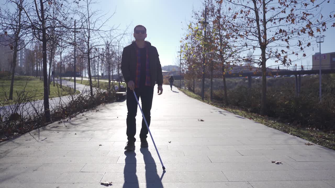 Blind man walking in the park with his cane.
