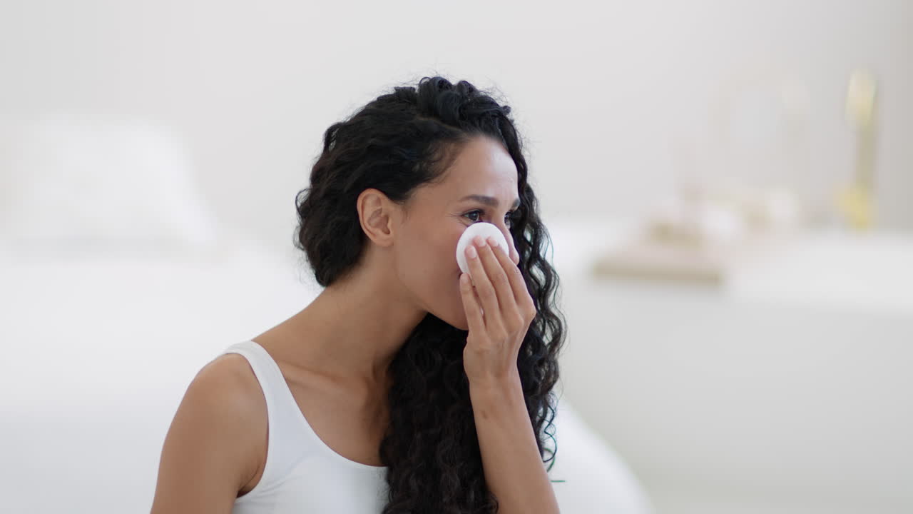 mujer limpiando la cara con una almohadilla de algodón