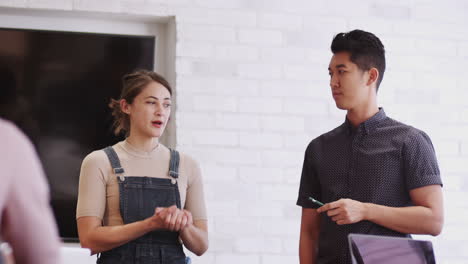 two millennial creative coworkers presenting to team in an office meeting room, selective focus