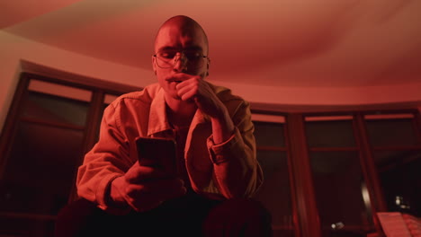 young man looking at smartphone in a red lit room