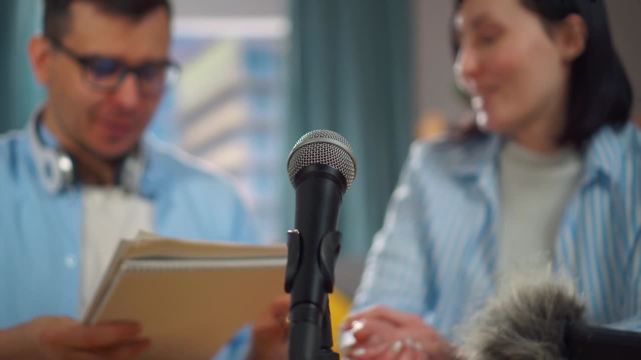 man with glasses and a woman record a live interview, microphone close up