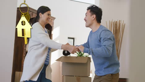 animation of gold house key and key fob over happy diverse couple dancing at new home