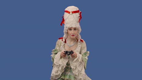 retrato de una dama de la corte con un vestido vintage y una peluca jugando a un videojuego usando un controlador inalámbrico, pierde. mujer joven posando en un estudio con fondo de pantalla azul. primer plano. cámara lenta lista 59.94fps