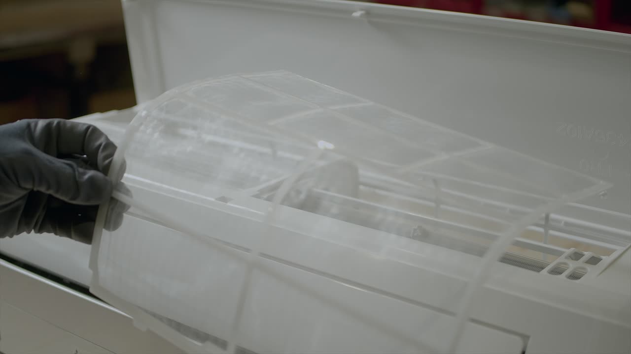 청소를 위해 에어컨 필터를 제거하는 전기 기술자
