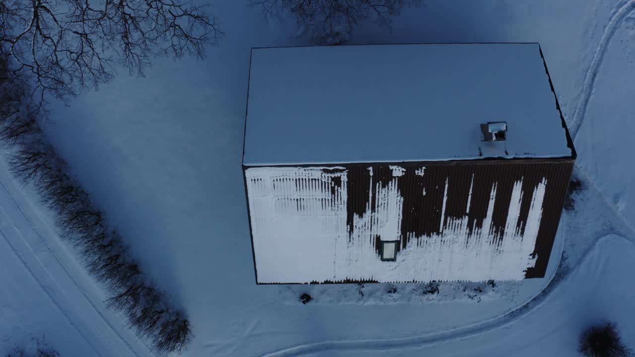 Aerial top down drone view of a single family home roof covered in snow on a winter day. From sunny to cloudy weather.