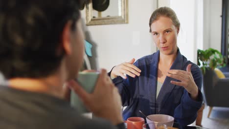 Mujer-Caucásica-Hablando-Con-Su-Esposa-Mientras-Desayuna-En-Casa