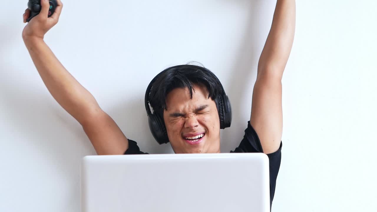 Young Asian gamer grinning stretches after playing games on his laptop