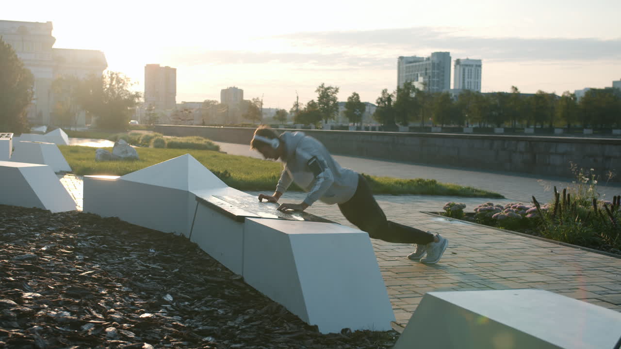 Man exercising outdoors in a city park at sunrise