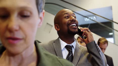 Businessman-talking-on-mobile-phone-while-standing-in-a-line