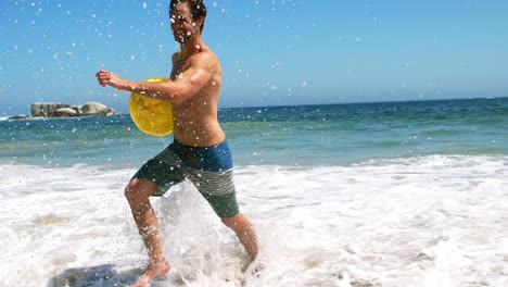 hombre saliendo del agua con una pelota de playa
