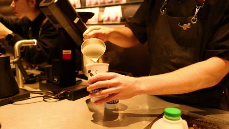 barista vertiendo leche en una taza de café