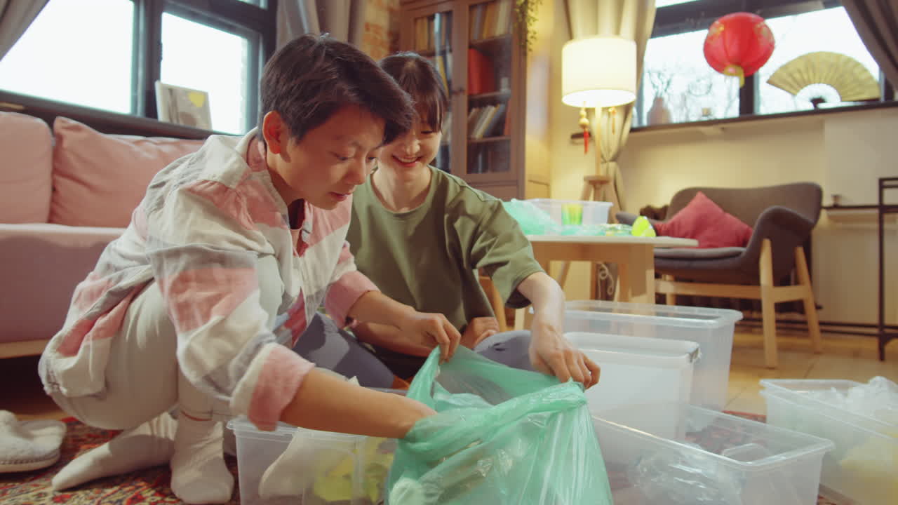 두 명의 아시아 여성이 집에서 쓰레기를 분류하고 있습니다.