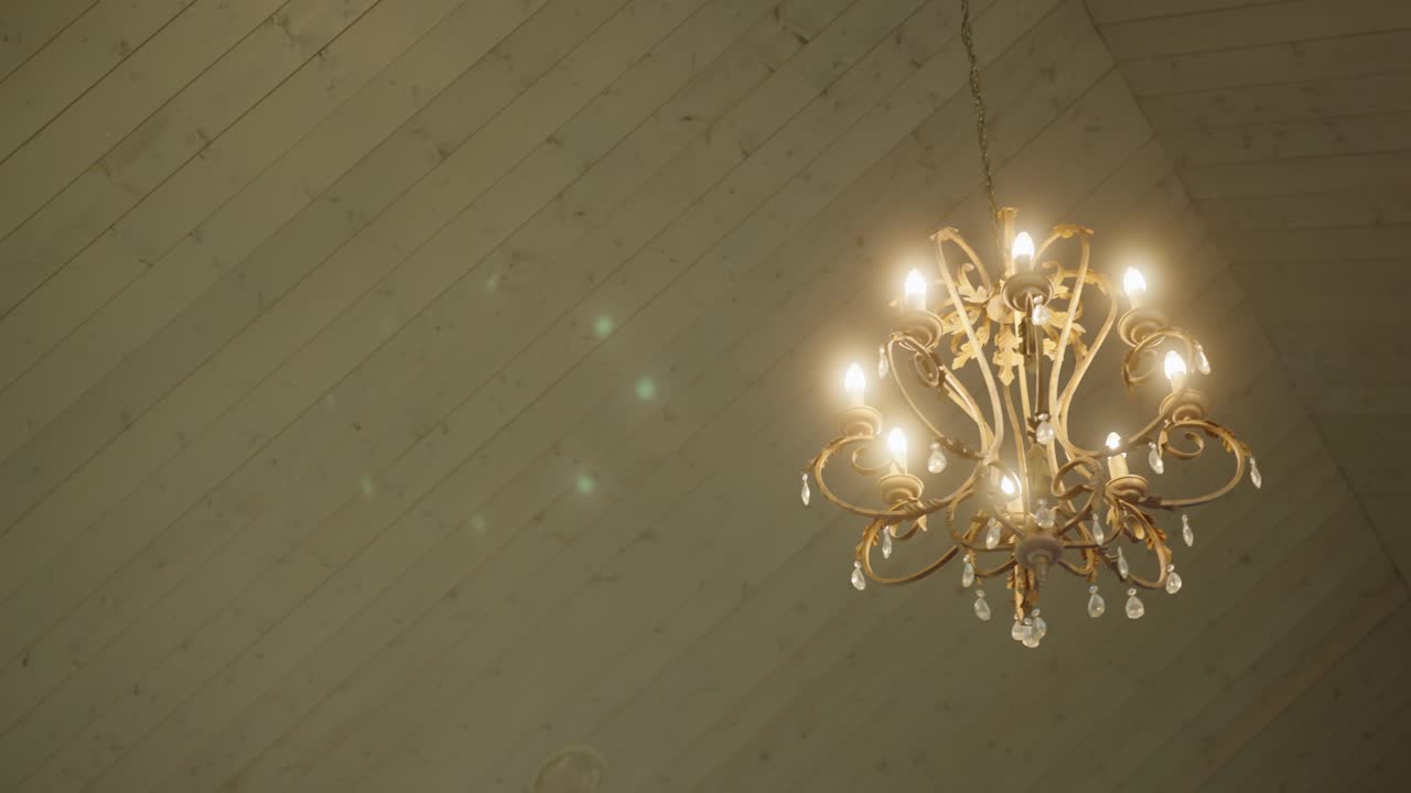Close-up of a classic gold chandelier hanging in a warmly lit interior, creating an elegant and timeless decorative atmosphere with vintage charm and luxury feel
