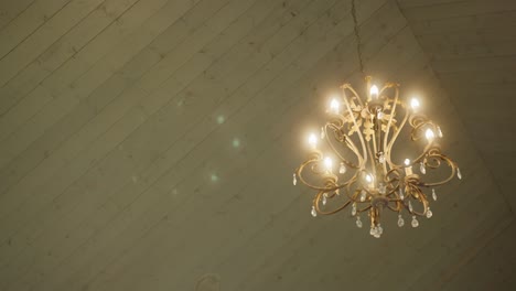close-up of a classic gold chandelier hanging in a warmly lit interior, creating an elegant and timeless decorative atmosphere with vintage charm and luxury feel